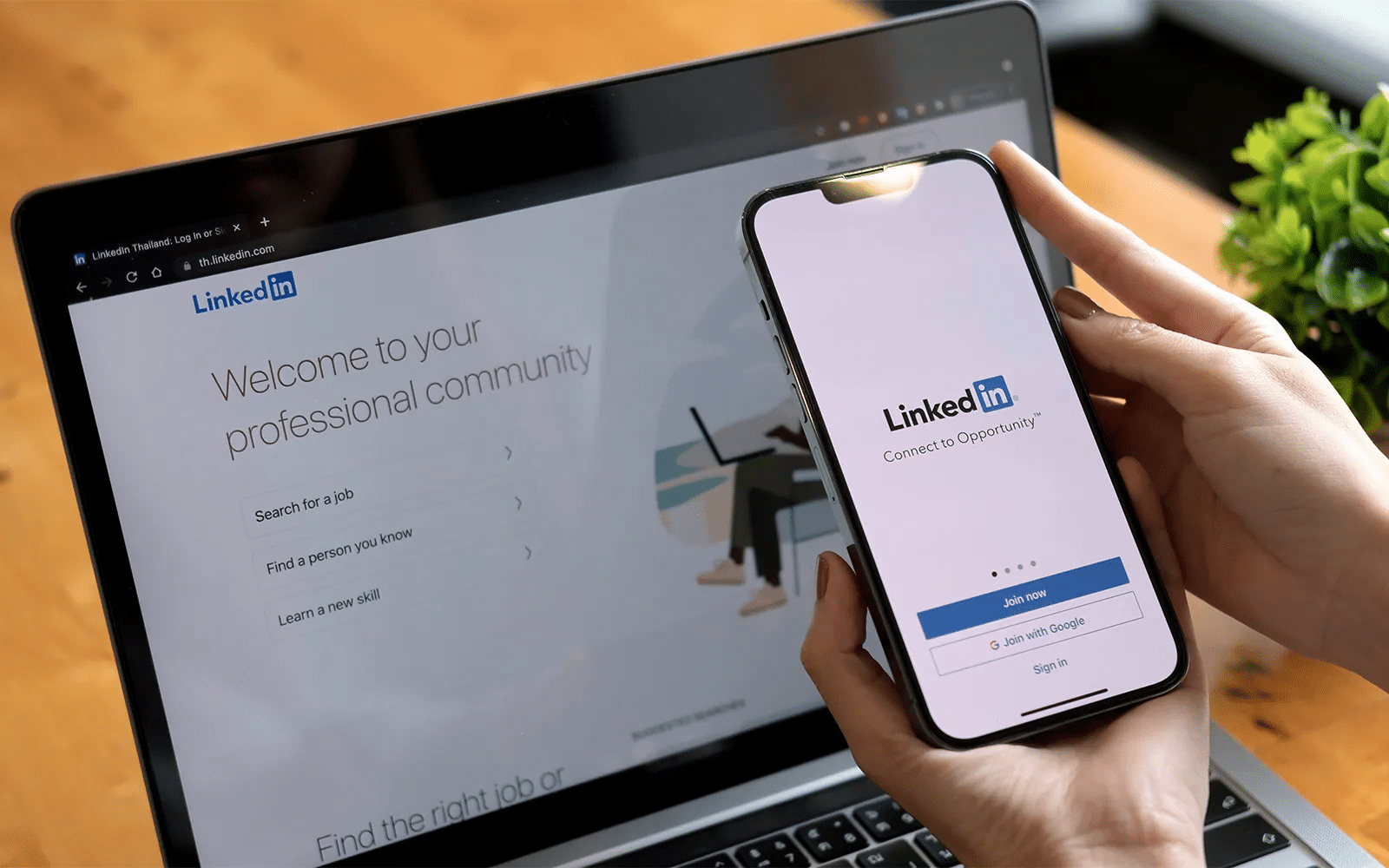 Person uses LinkedIn on a laptop and a smartphone side-by-side show screen with LinkedIn login and homepage elements.